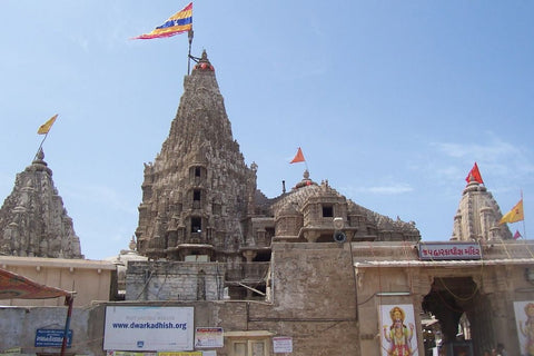 Dwarkadhish Temple in Dwarka, India, with tall carved stone spires and flags flying against a blue sky