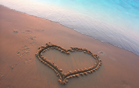 Heart drawn in the sand at the edge of the ocean