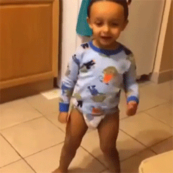 Animated GIF of a toddler in a diaper and dinosaur pajama top dancing on a kitchen floor