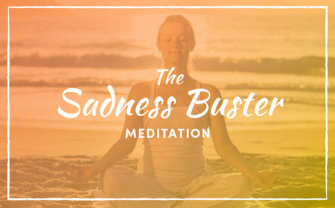 Woman meditating cross-legged on a beach under the title The Sadness Buster Meditation