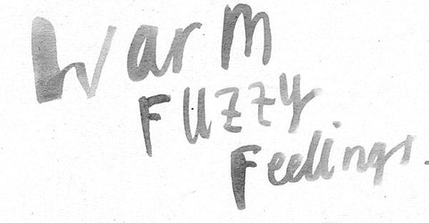 Hand-painted gray brush lettering reading Warm Fuzzy Feelings