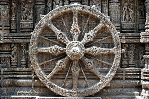 Large carved stone wheel with ornate spokes set into a sculpted temple wall