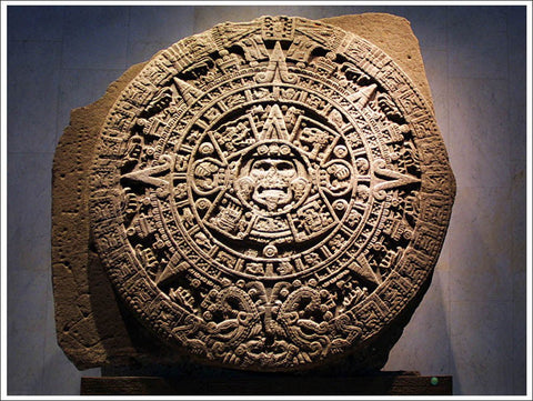 Carved stone Aztec Sun Stone calendar with a central face and rings of glyphs, displayed in a museum