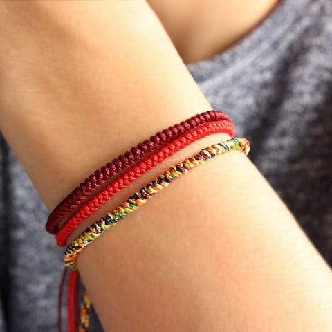 Wrist wearing red, maroon and multicolor Tibetan Buddhist knot bracelets