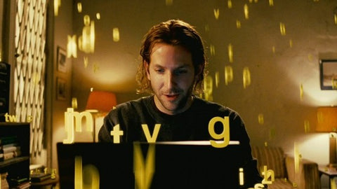 Film still of a man at a laptop surrounded by floating yellow letters