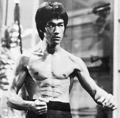Bruce Lee, shirtless, in a fighting stance in a black-and-white film still
