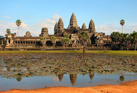 Angkor Wat temple towers reflected in a lily pond under a blue sky